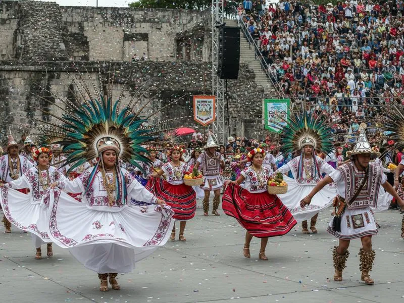 Traditional Guelaguetza festival in Oaxaca City with indigenous dancers in colorful regional costumes performing at the Guelaguetza Amphitheater in July