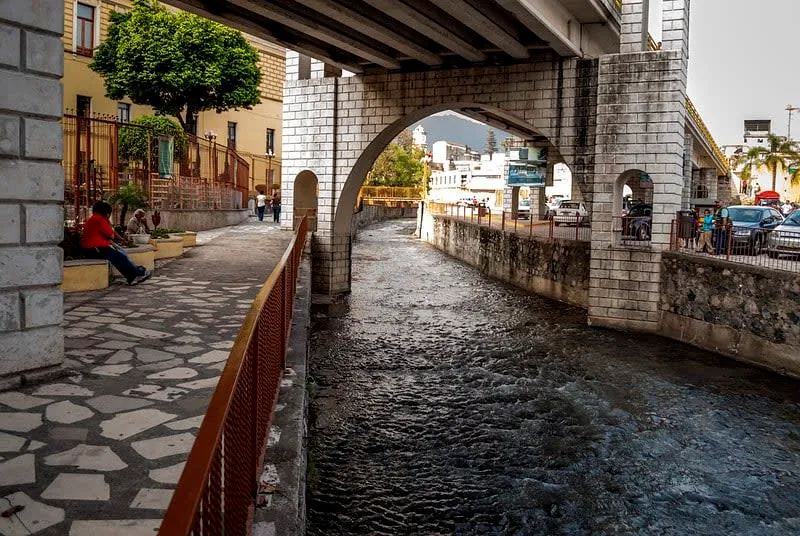 Green river walk in central Orizaba with paths and trees beside the water