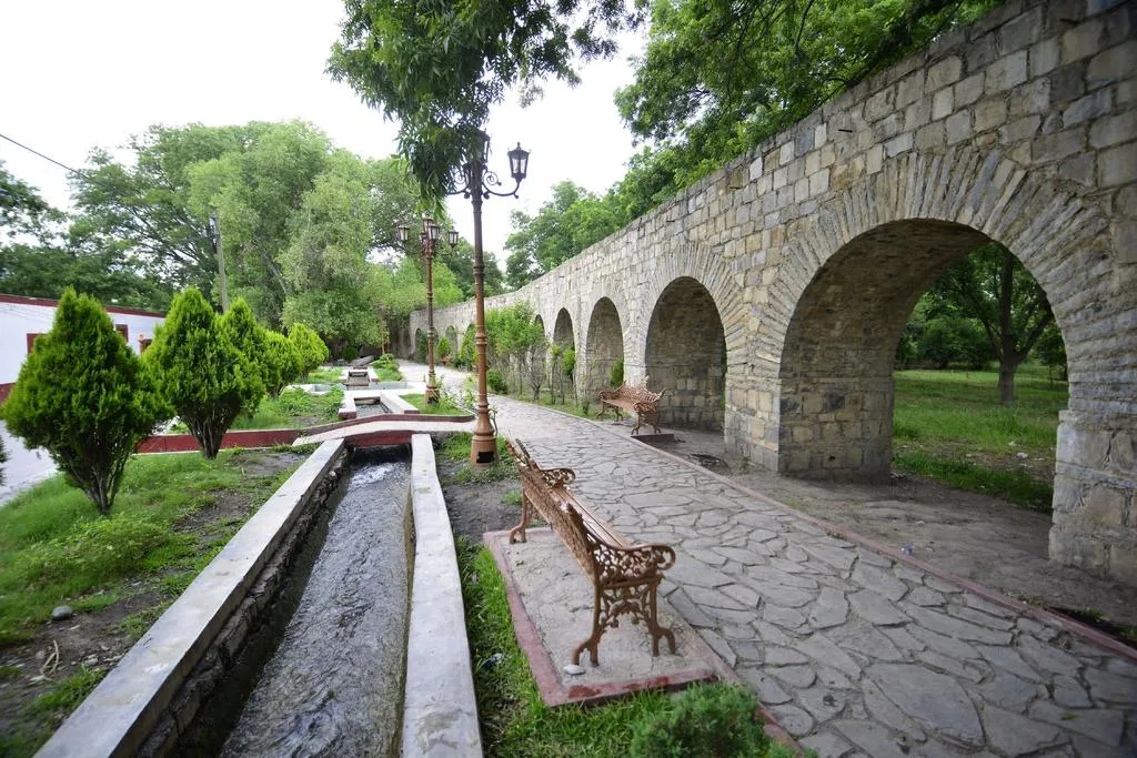 Stone aqueduct and shaded water channel in Parras