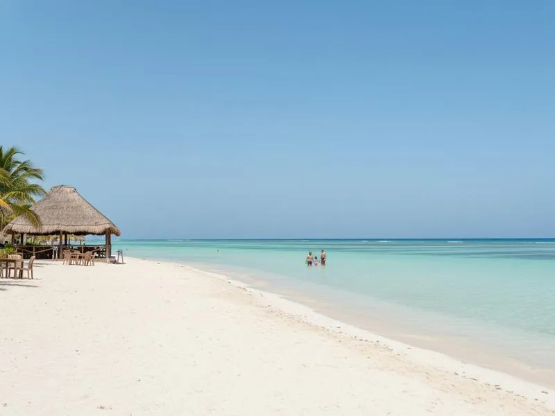 Playa Norte beach on Isla Mujeres Mexico with turquoise water so shallow and calm that families with young children can play far from shore, white sand, palm trees, small beach restaurants in background