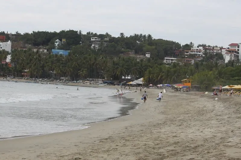 Playa Marinero shoreline with small surf waves and palapa cafe tables