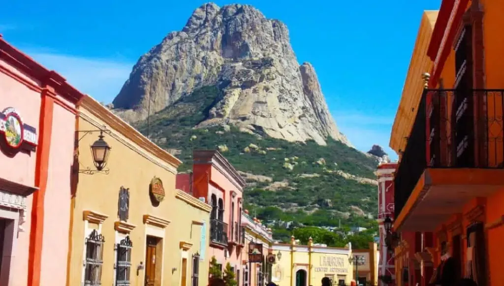Peña de Bernal monolith rising above the colonial village of Bernal, Querétaro — the world's third-largest freestanding rock formation towering over ochre buildings and church steeples