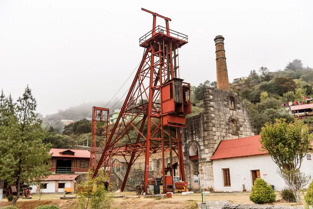 Visitors walking between stone buildings at the Acosta Mine site