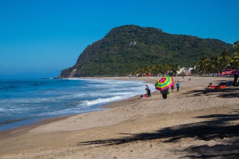 Lo de Marcos beach framed by palms, hills, and a quiet bay