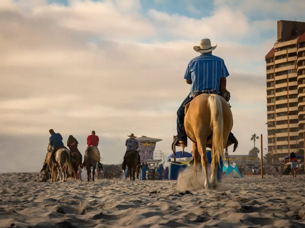 Horseback riders moving along the sand on Rosarito Beach