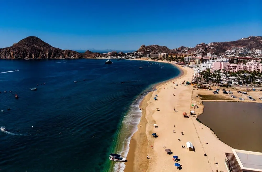 Wide sandy shoreline and calm water at Medano Beach in Cabo San Lucas