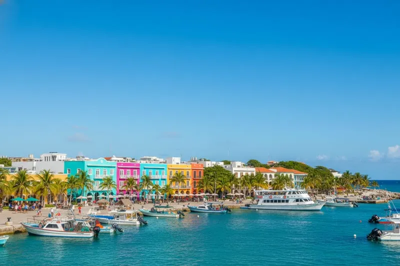 San Miguel de Cozumel waterfront avenue with cruise ship visible in port and Mexican colonial buildings along the seaside promenade