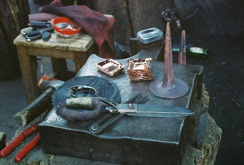 Artisan hands hammering a copper sheet in a traditional workshop in Santa Clara del Cobre, Michoacán — the pre-Columbian Purépecha copper-working technique still practiced today