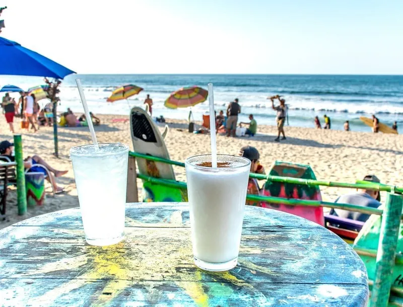 Small waves rolling toward Sayulita's sandy surf beach below palm-covered hills