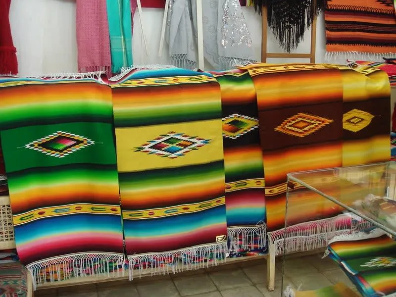 Stack of Mexican serapes with bold woven stripes in many colors