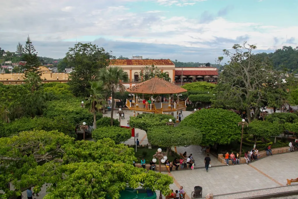 Main square park with shaded paths, benches, and a painted kiosk ceiling