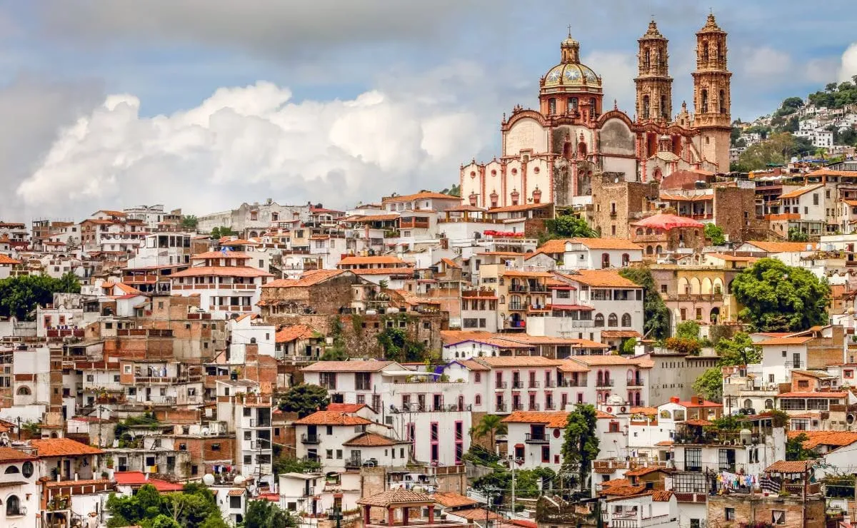 Panoramic view of Taxco de Alarcón with white colonial buildings cascading down the hillside and Santa Prisca cathedral twin towers rising above the city