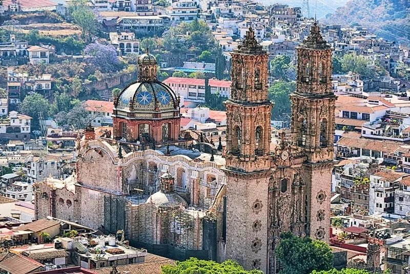 Panoramic view of Taxco, Guerrero with white colonial buildings cascading down the hillside and Santa Prisca Church at center