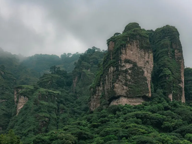 View of Tepoztlan with dramatic volcanic cliff formations rising above the colonial town and El Tepozteco pyramid visible on the peak
