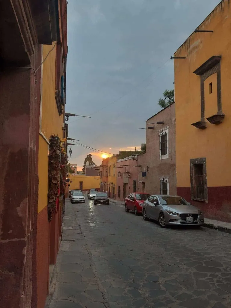 Cobblestone street with colorful colonial buildings and flower-draped walls in San Miguel de Allende historic center