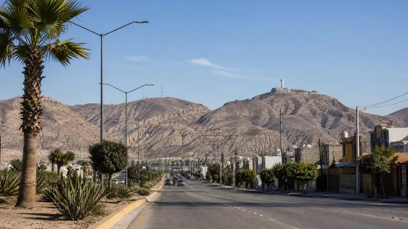 Dry November road into Torreon with desert hills and Cristo de las Noas above the city