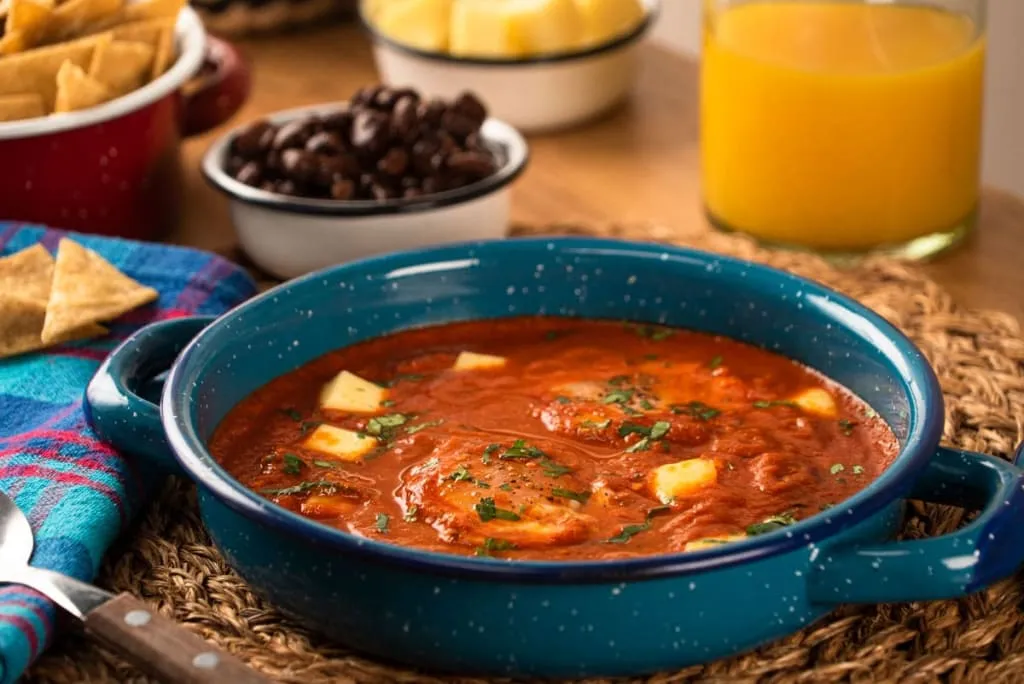 Huevos ahogados poached in red salsa and served in a bowl