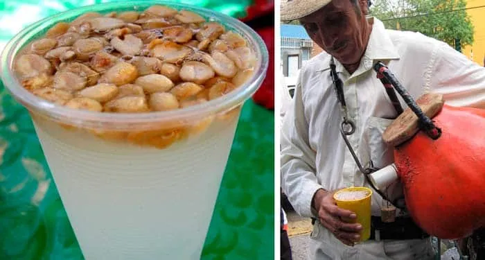 Glass of pink tuba drink with floating peanuts diced apple and strawberry — traditional Mexican fermented beverage from Colima