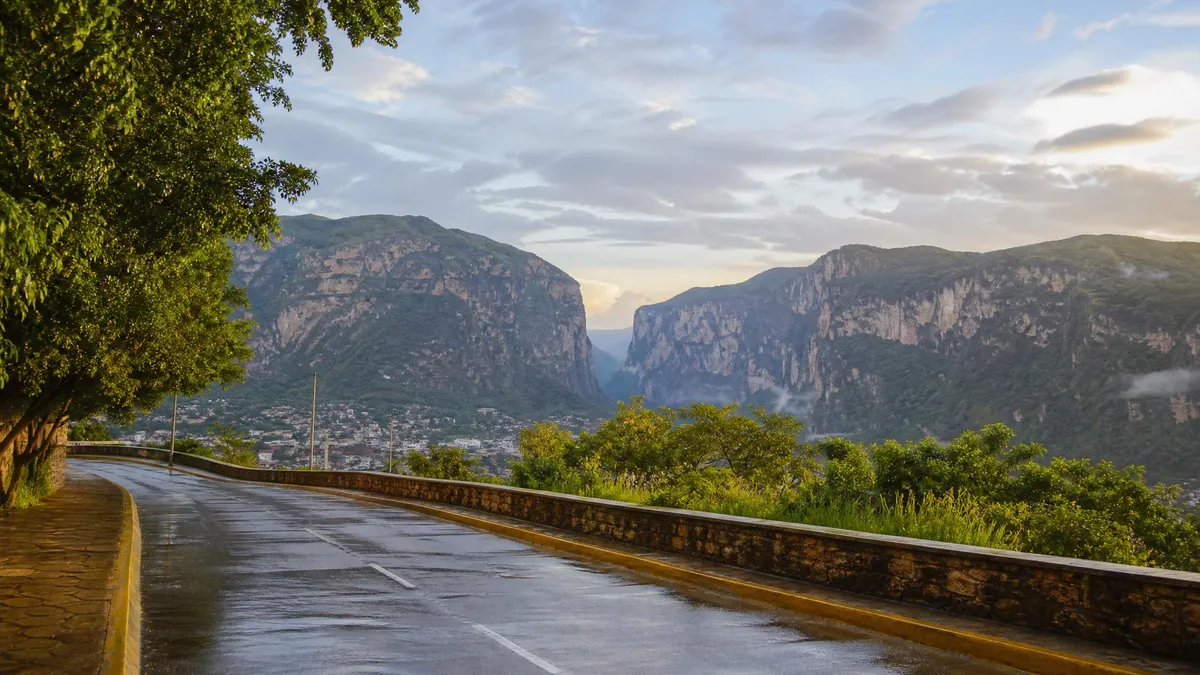 Rain-wet road below green Chiapas hills and Sumidero Canyon cliffs after an early-summer shower