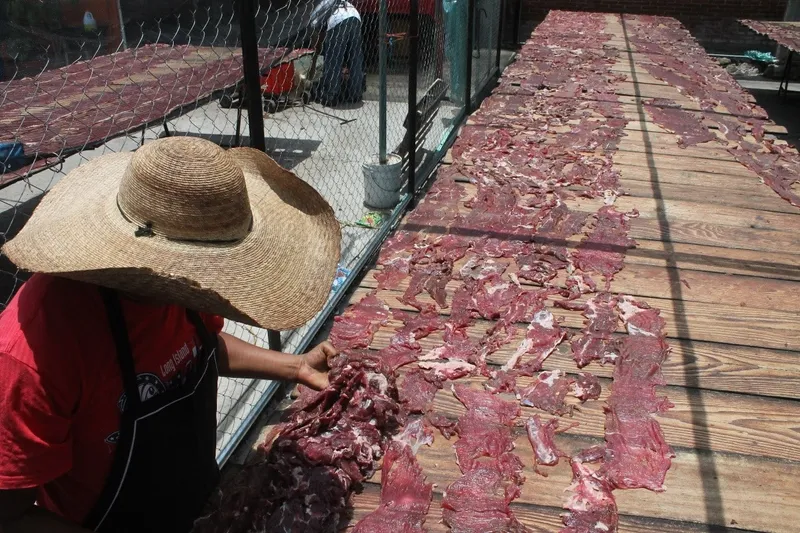 Thin sheets of cecina de res air-drying on wooden poles at a Yecapixtla market stall, Morelos, Mexico