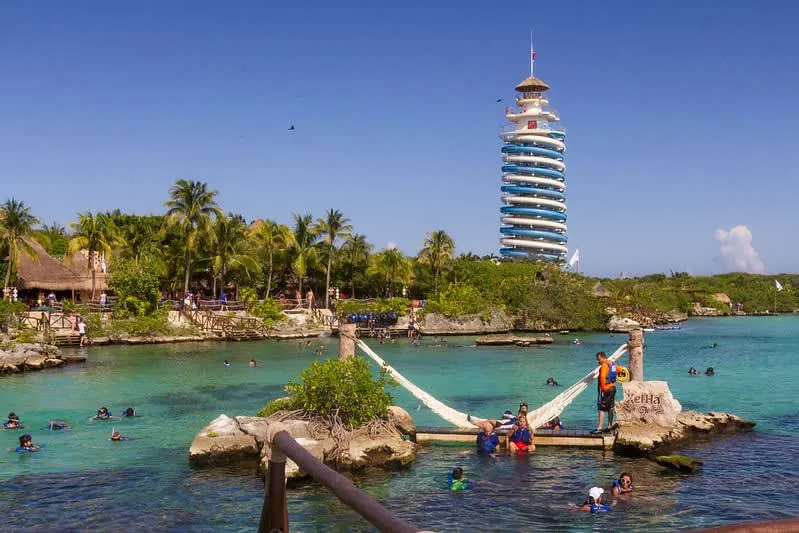Lagoon with swimmers, hammocks, palm trees, and a tall spiral tower