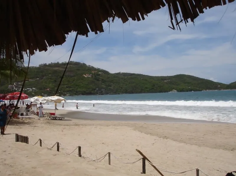 Blue Zihuatanejo Bay with beach umbrellas along the shore