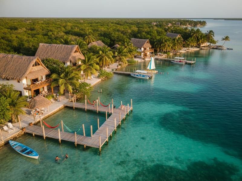 Lakefront Bacalar hotel dock with palapa shade and calm blue water after morning sun