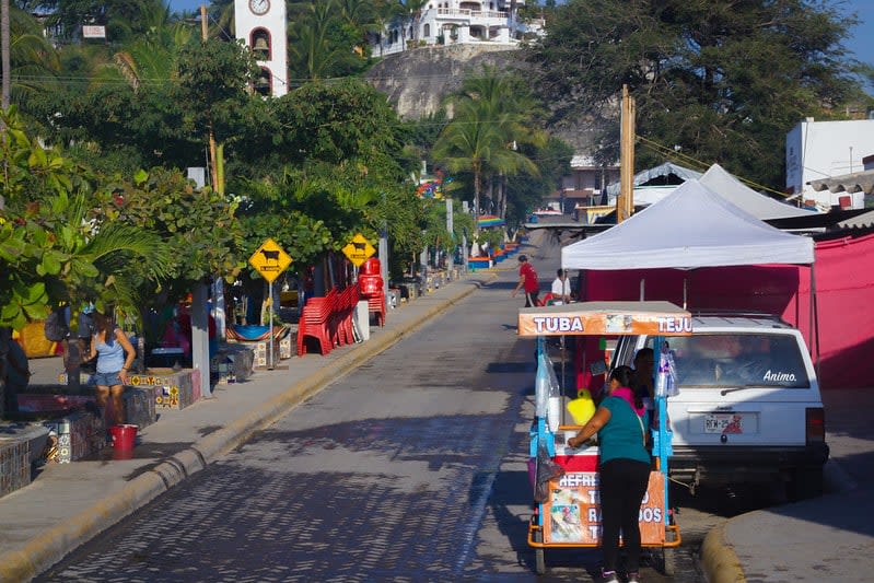 Cobblestone street lined with colorful buildings and parked cars