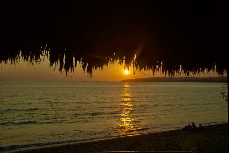 Orange sunset over the beach with silhouettes of people on the sand