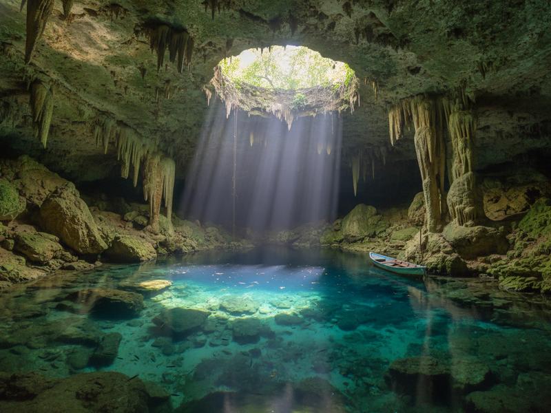 Scuba diver exploring Cenote Dos Ojos cave system near Tulum Mexico with stalactites and crystal clear water