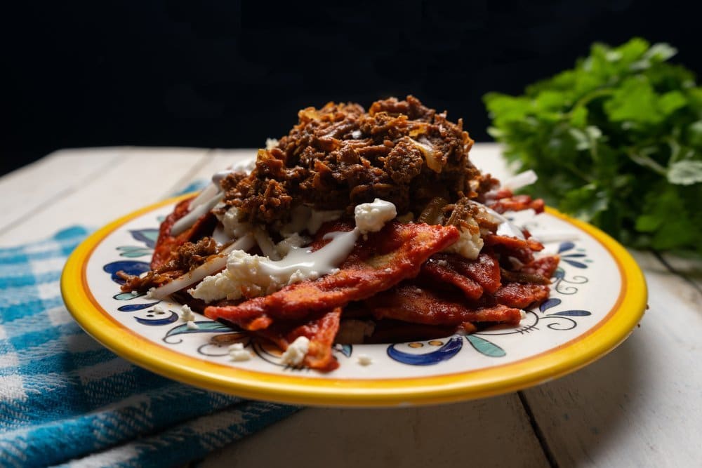 Plate of chilorio-style tortilla chips topped with cream and cheese