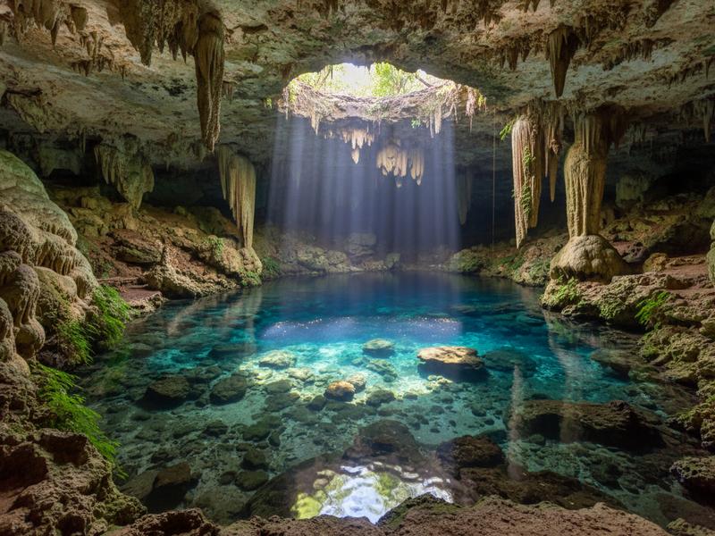 Entrance path to Gran Cenote Tulum through jungle with limestone formations and visitors