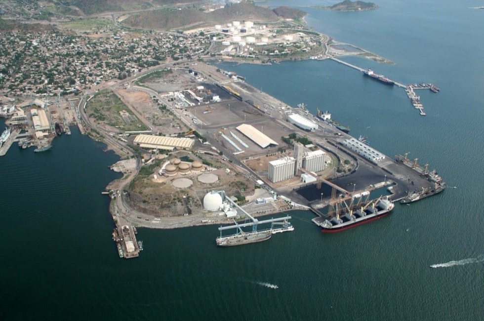 Boats in Guaymas harbor under strong June sun with dry Sonoran hills beyond the water