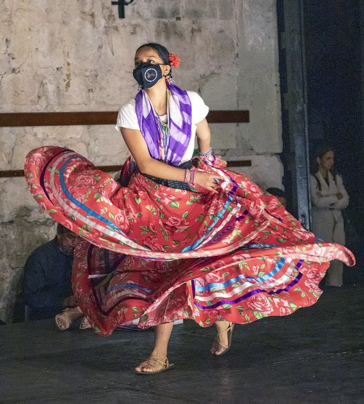 Colorfully dressed Guelaguetza dancers performing traditional Oaxacan regional dance on the hillside stage