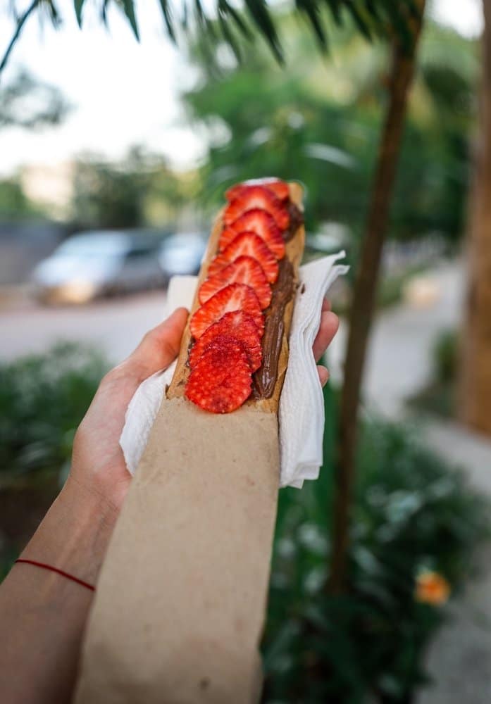 Hand holding a marquesita filled with chocolate and strawberries