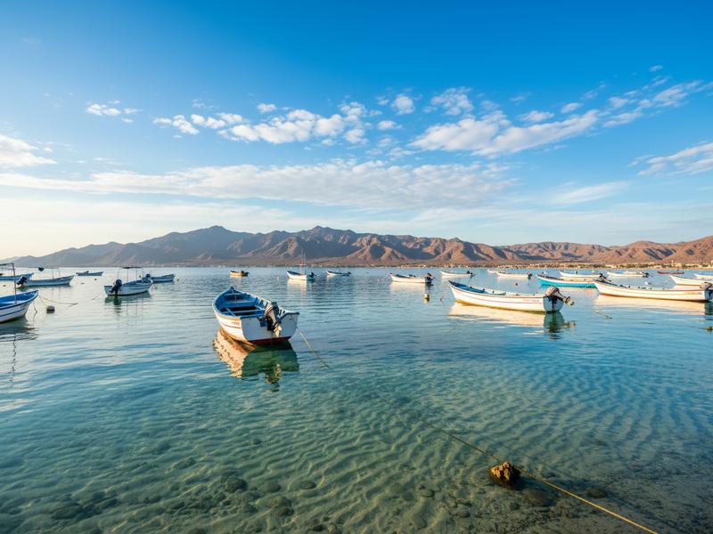 traditional fishing boats anchored in turquoise waters of la paz bay with mountains in background sea of cortez