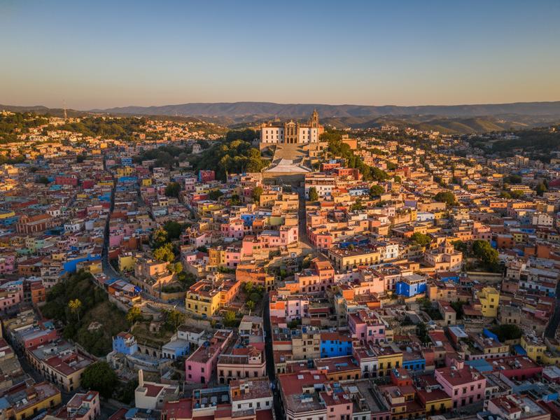 Panoramic view of Guanajuato's colorful houses cascading up a hillside with the university building visible