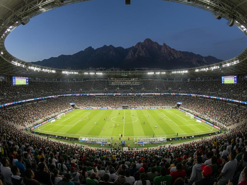 Interior of Estadio BBVA with a match in progress and the Sierra Madre mountains visible above the stands