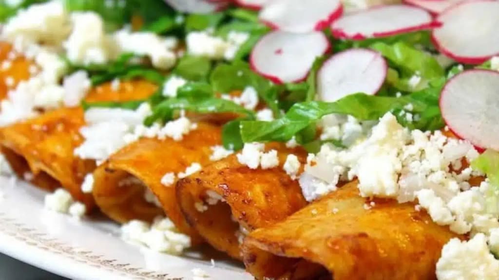Enchiladas Zacatecanas topped with cream, queso fresco, and raw onion